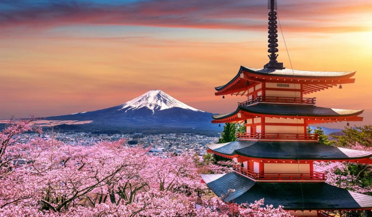 A tall Japanese tower against the backdrop of a megalopolis and mountains